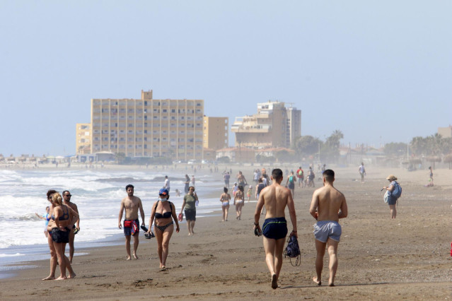 Paseantes disfrutan de la playa de Huelín durante la Fase 1 del Estado de Alarma.
