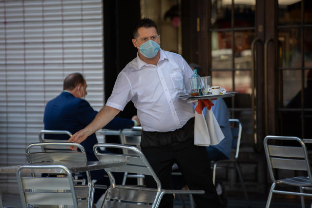 Un camarero sirve en la terraza de un bar de Barcelona