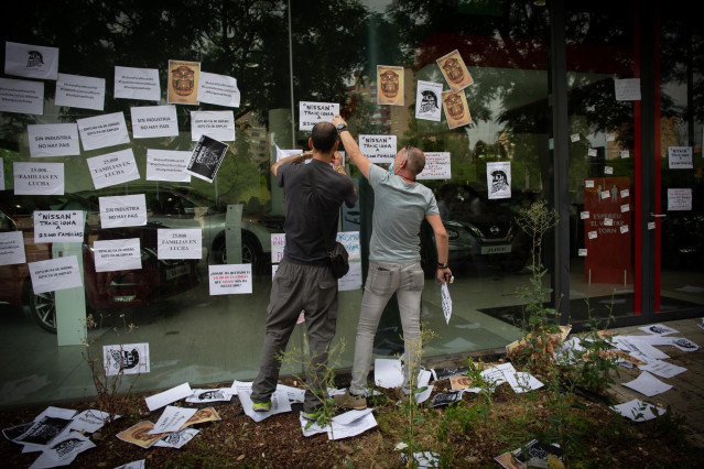 Varios trabajadores de Nissan cuelgan carteles como signo de protesta en el corte que han realizado en la Gran Vía de L’Hospital (Barcelona), cerca del concesionario de Nissan Motor Llansà, uno de los cuatro concesionarios donde los comités de empresa del