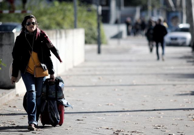 Una mujer camina con su maleta por una calle de Madrid.