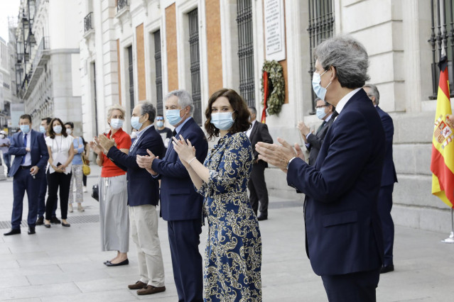 La presidenta de la Comunidad de Madrid, Isabel Díaz Ayuso (2d), con representantes del sector sanitario aplauden tras guardar un minuto de silencio junto con otras personalidades en memoria por los fallecidos por el COVID-19 en la Puerta de Sol