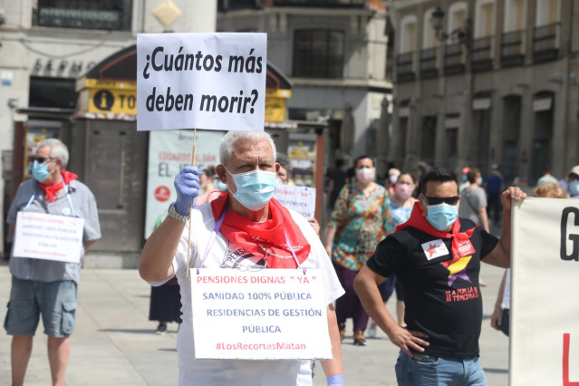 Un miembro del Movimiento Pensionista de Madrid sostiene un cartel en el que se lee '¿Cuántos más deben morir?'
