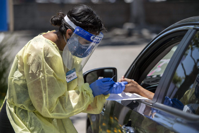 03 June 2020, US, Los Angeles: A medical worker wears protective equipment takes a sample from a person at a drive-through COVID-19 testing clinic at the Weingart YMCA Wellness and Aquatic Center. Photo: Hans Gutknecht/Orange County Register via ZUMA/dpa