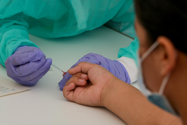 Una trabajadora sanitaria totalmente protegida, realiza una prueba diagnóstica del coronavirus