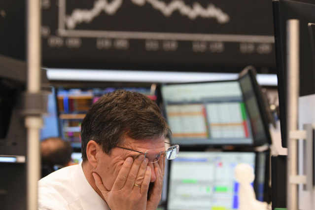 09 March 2020, Hessen, Frankfurt/Main: A stock trader rubs his eyes on the floor of the Frankfurt Stock Exchange. Stock exchanges around the world are reacting with huge losses to the fall in oil prices and concerns about the economic consequences of the