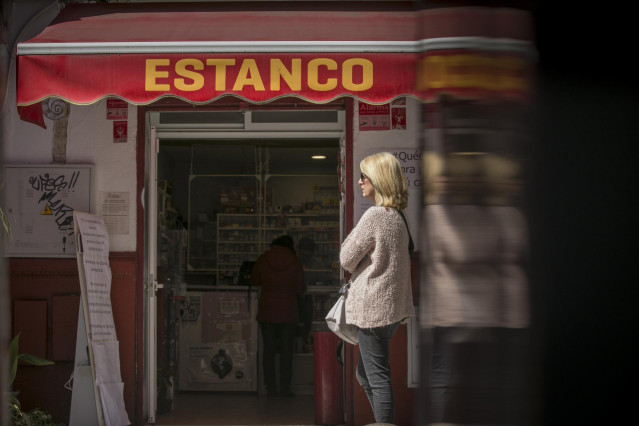 Una mujer guarda cola en un estanco, abierto por ser esencial, durante la limitación total de movimientos salvo de los trabajadores de actividades esenciales, medida adoptada por el Gobierno como prevención del coronavirus durante el estado de alarma. En