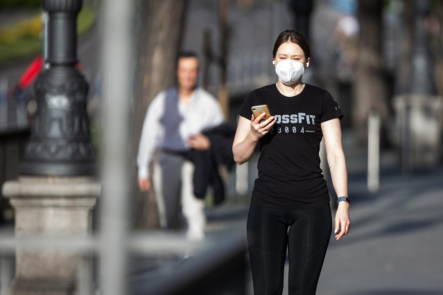 Una mujer con mascarilla hace una foto con el móvil en Madrid en el segundo día de desconfinamiento durante la Pandemia Covid-19 que ha generado el Estado de Alarma en España.