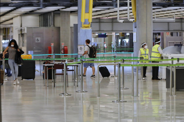 Pasajeros procedentes de Londres caminan entre los pasillos delimitados, antes de rellenar un formulario, a su llegada al Aeropuerto de Madrid-Barajas Adolfo Suárez, como medida de control de los casos sospechosos de coronavirus cuatro días después desde