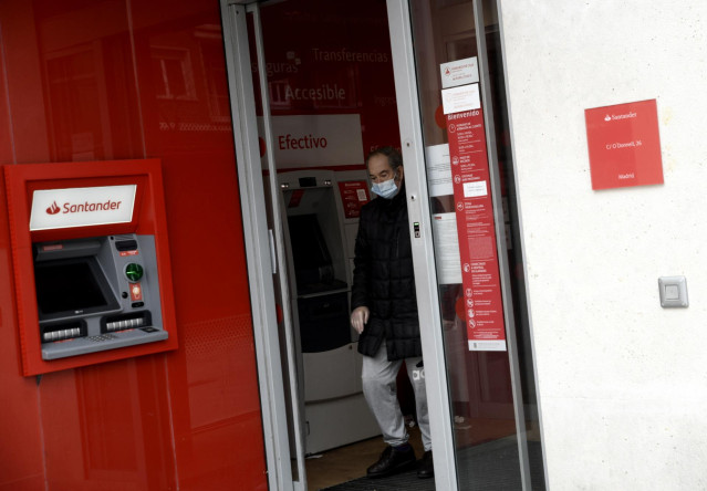 Un hombre saca dinero de un cajero del Banco Santander.