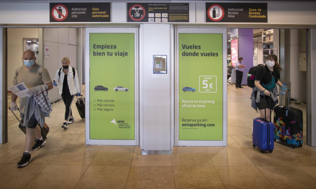 Varias personas protegidas con mascarillas salen de la Terminal T1 del Aeropuerto Adolfo Suárez Madrid-Barajas