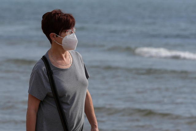 Una mujer con mascarilla paseando.