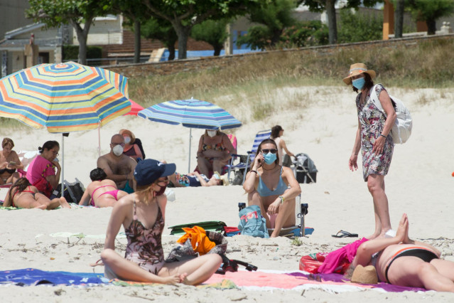Varias personas protegidas con mascarillas en una playa en A Mariña.