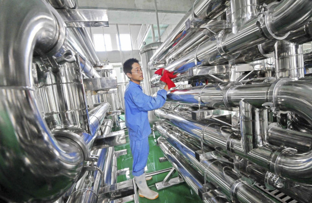 Un empleado limpia unos equipos en una fábrica de vinos en Weifang (China)