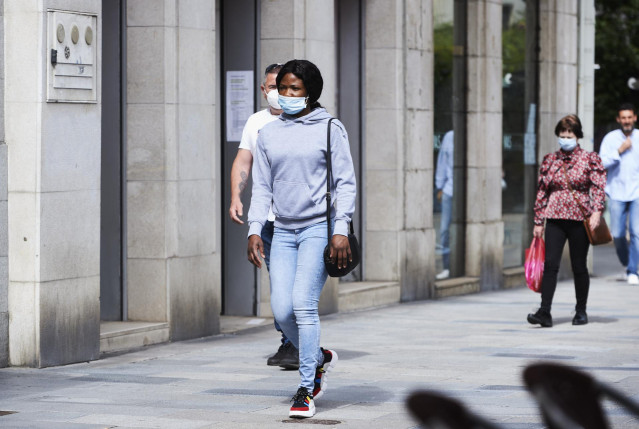 Transeúntes pasean por calles de Santander con mascarilla.