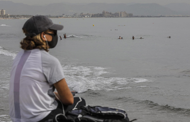 Una mujer protegida con mascarilla en la Playa de la Malvarrosa