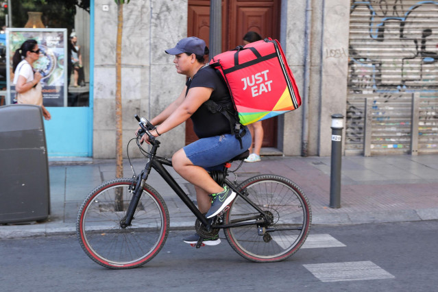 Repartidor de la empresa de reparto Just Eat transitando en bicicleta por una calle del centro de Madrid.