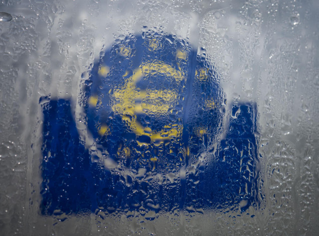 FILED - 19 March 2020, Hessen, Frankfurt_Main: Water droplets slide down the glass covering the euro symbol at the south entrance to the headquarters of the European Central Bank (ECB). The global economy will contract 3 per cent this year due to the new