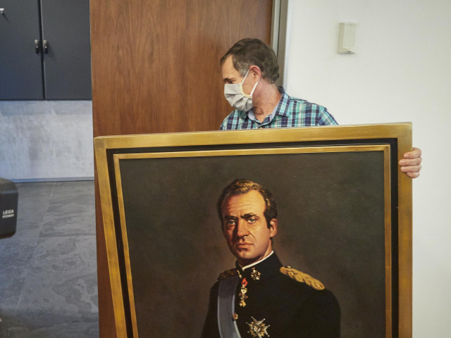 Un operario retira el retrato del rey emérito Juan Carlos I de la Sala de Gobierno del Legislativo foral del Parlamento de Navarra horas después de que la Junta de Portavoces aprobase el acto con los votos del Partido Socialista de Navarra, Geroa Bai, EH