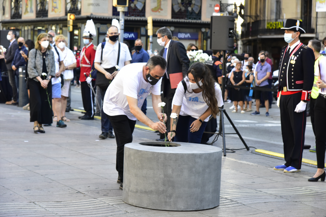 Asistentes dejan rosas blancas y carteles en recuerdo a las 16 personas fallecidas el 17 de agosto de 2017 y a los más de 150 heridos en los atentados de Barcelona y Cambrils durante el homenaje y minuto de silencio celebrado en Las Ramblas con motivo del