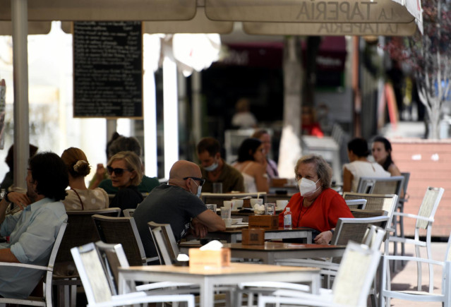 Varias personas disfrutan en una terraza de un bar el día en el que entra en vigor en la Comunidad de Madrid la ampliación del uso obligatorio de la mascarilla, la limitación de las reuniones en terrazas a grupos de un máximo de diez personas y las restri