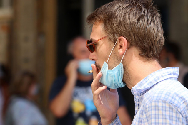 Una persona fuma en la calle durante el primer día de la prohibición de realizarlo en la vía pública en Andalucía.