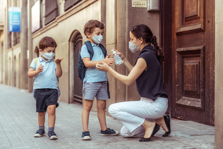 Uso de geles hidroalcohólicos  en niños. Madre con dos niños.