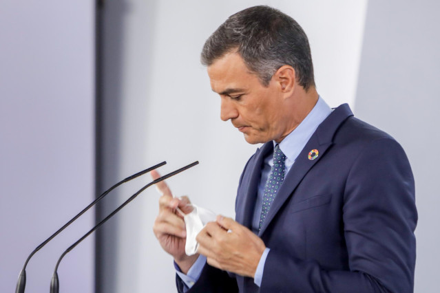 El presidente del Gobierno, Pedro Sánchez, se retira la mascarilla antes de ofrecer una rueda de prensa
