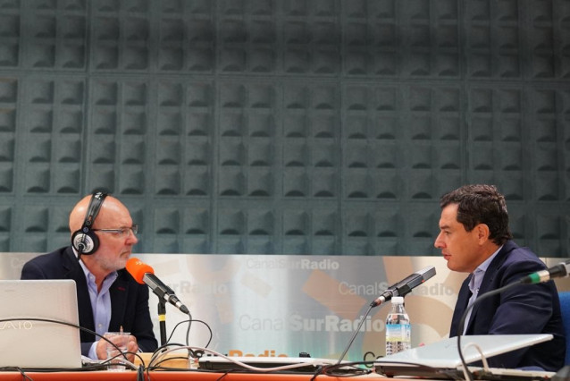 El presidente de la Junta de Andalucía, Juanma Moreno (d.), durante la entrevista, este lunes, con el periodista Jesús Vigorra (i.)