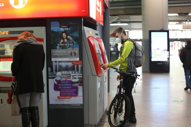 Un viajero con bicicleta adquiere un billete en un dispensador en la estación de Atocha