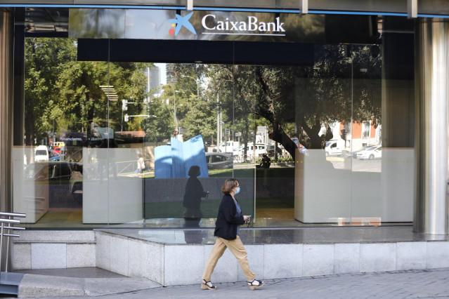 Una mujer pasa por al lado de las oficinas de Caixabank en el Paseo Castellana, en Madrid (España) a 4 de septiembre de 2020. CaixaBank y Bankia estudian emprender un proceso de fusión con el fin de aumentar su rentabilidad ante la crisis provocada por la