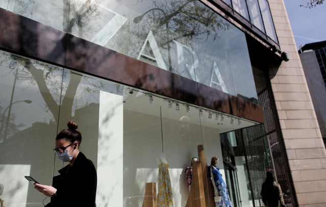 Una mujer con mascarilla pasa junto al escaparate de la tienda Zara de la Calle Princesa de Madrid del grupo Inditex, tras el anuncio de este grupo del cierre de todas sus tiendas temporalmente en Madrid, La Rioja, Vitoria y Miranda de Ebro por la crisis