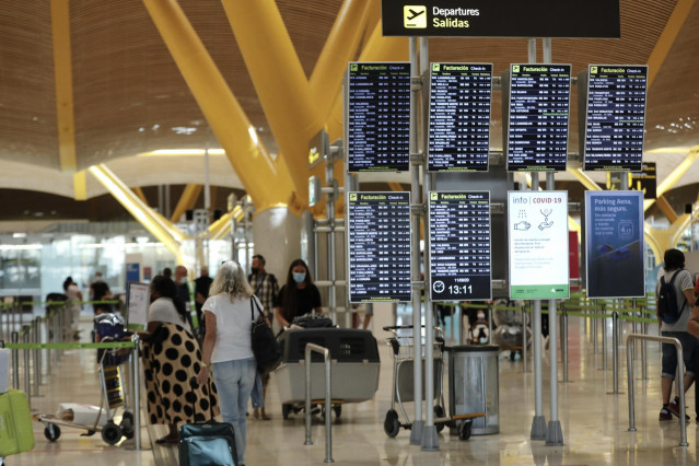 Pasajeros junto a páneles de información en la Terminal T4 del aeropuerto Adolfo Suárez Madrid-Barajas, en Madrid (España).