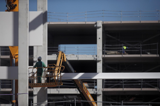 Varios obreros trabajan con maquinaria de construcción.