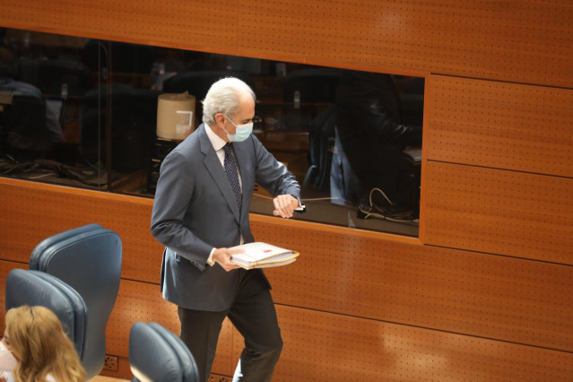 El consejero de Sanidad de la Comunidad de Madrid, Enrique Ruiz Escudero, con mascarilla, mira el reloj en la Asamblea de Madrid durante la sesión de control al Gobierno en la Asamblea de Madrid en la que se debate sobre derechos LGTBI, medicalización de