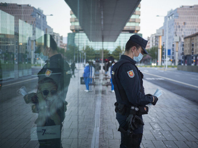 Un policía nacional se prepara para un dispositivo de control por la pandemia de COVID-19