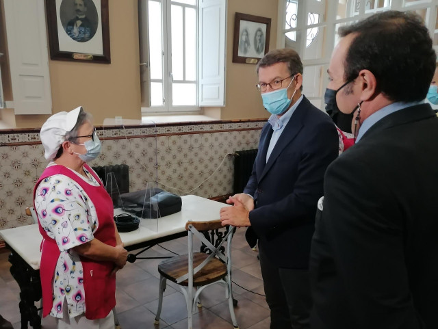 El presidente de la Xunta, Alberto Núñez Feijóo, saluda a una trabajadora de la Cocina Económica