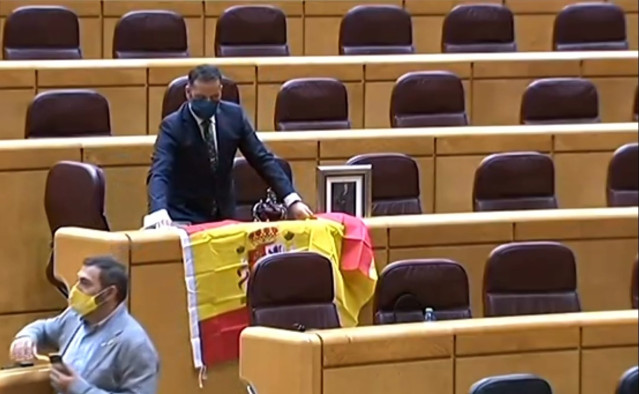 Un senador del PP recibe a Iglesias con la bandera de España y una foto del Rey.