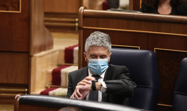El ministro de Interior, Fernando Grande-Marlaska, consulta la hora durante una nueva sesión de control al gobierno en el Congreso