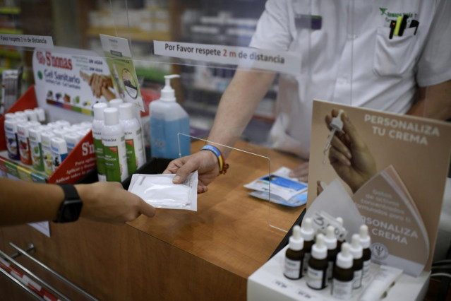Un farmacéutico entrega a un cliente una de las mascarillas KN95
