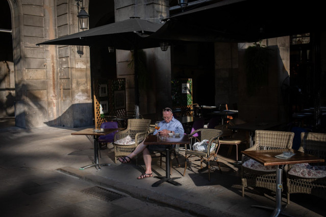 Un hombre consulta su teléfono móvil en la terraza de un bar en Barcelona, Cataluña (España) a 14 de octubre de 2020.