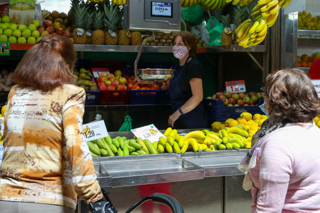 Una trabajadora de una frutería del Mercado Central de Valencia atiende a dos clientas