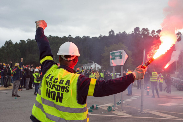 Un trabajador sostiene una bengala durante una nueva manifestación convocada por el Comité de Alcoa en la que cortan el tráfico en la carretera N-642 y el acceso al corredor C.G.2.3 a la altura de Lago, en Xove, Lugo