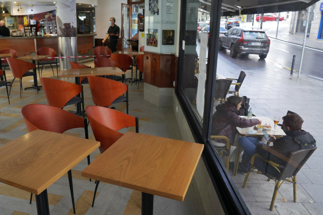 Dos personas toman el aperitivo en una mesa de la terraza de un bar, en Santiago de Compostela, A Coruña (Galicia)