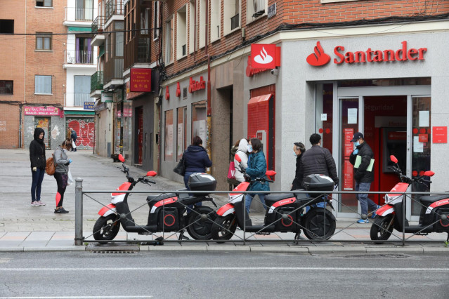 Varias personas esperan para entrar a una oficina del Banco Santander durante el inicio de la cuarta semana del estado de alarma decretado a consecuencia del coronavirus. En Madrid (España), a 6 de abril de 2020.