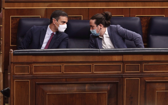 El presidente del Gobierno, Pedro Sánchez (i); y el vicepresidente segundo del Gobierno, Pablo Iglesias, mantienen una conversación durante la segunda sesión del pleno en el que se debate la moción de censura planteada por Vox.
