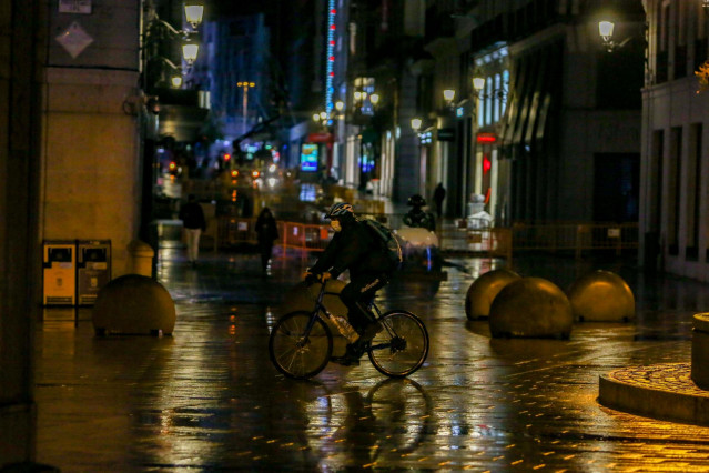 Un rider circula durante la primera noche de toque de queda en Madrid (España)