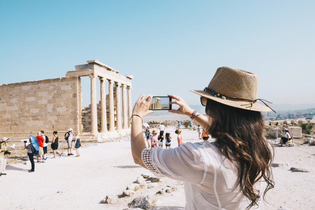 Un mujer hace una foto con su teléfono móvil en la Acropolis de Atenas (Grecia)
