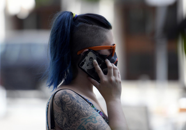 Una mujer con mascarilla habla por teléfono a 30 de julio de 2020