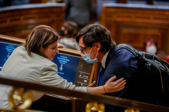 La vicesecretaria General del PSOE, Adriana Lastra, tiende el brazo al ministro de Sanidad, Salvador Illa, durante una sesión plenaria en la que el Gobierno solicita al Congreso la prórroga del estado de alarma debido a la crisis sanitaria del Covid-19, e