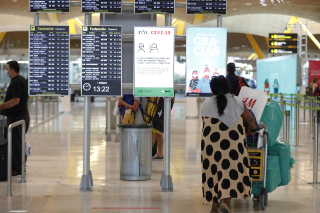 Pasajeros cerca de páneles informativos en la terminal T4 del aeropuerto Adolfo Suárez Madrid-Barajas